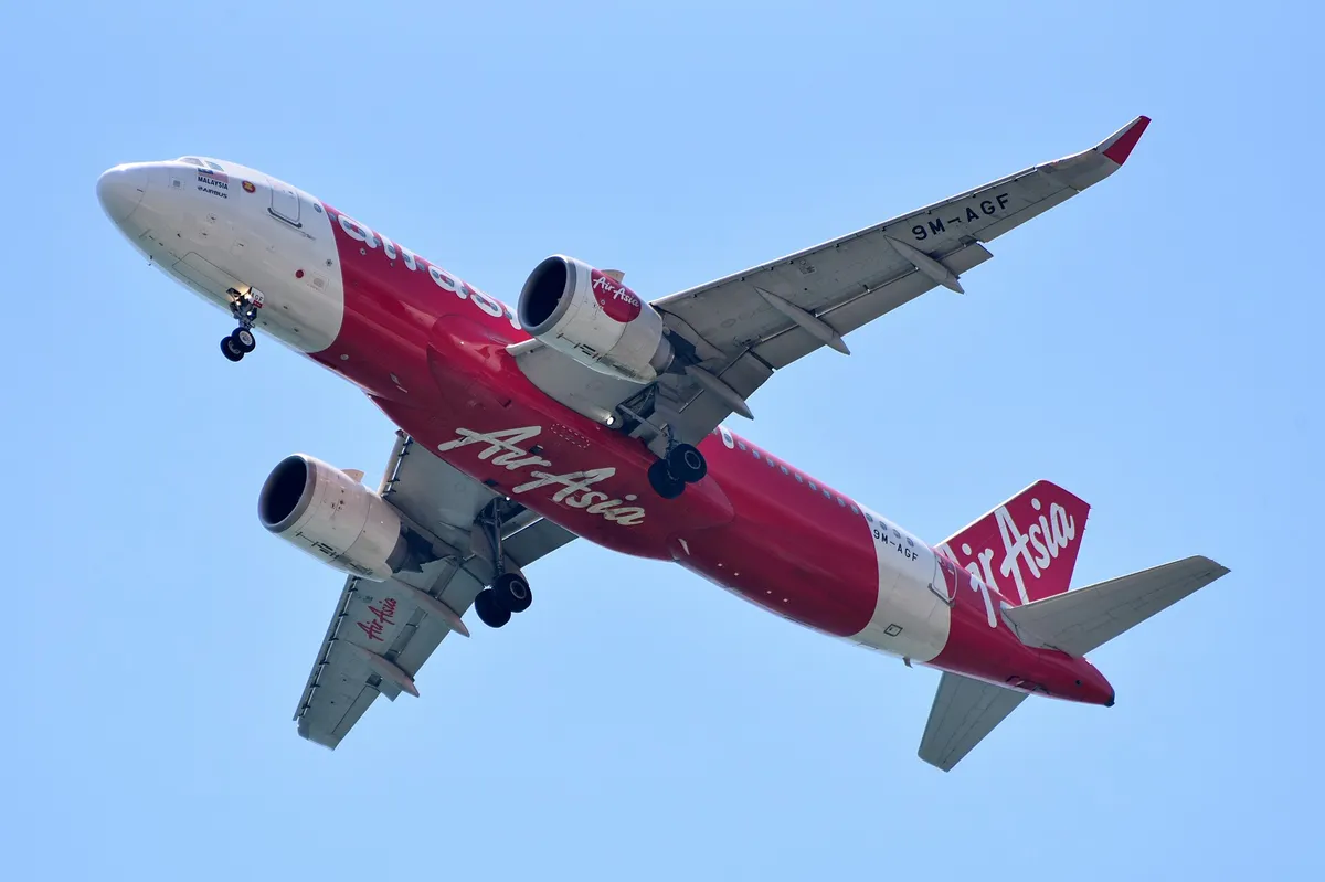 AirAsia Airbus A320neo climbing away against a clear blue sky, three-quarter view showing its CFM LEAP engines and wingtip fences.
