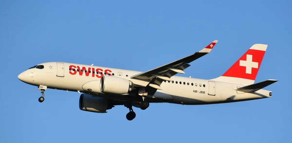 Swiss International Air Lines Airbus A220-100 HB-JBB on final approach in a three-quarter view against a clear blue sky, filling the frame and showing the slender body, curved wingtip blades, and oversized Pratt & Whitney engine pods.