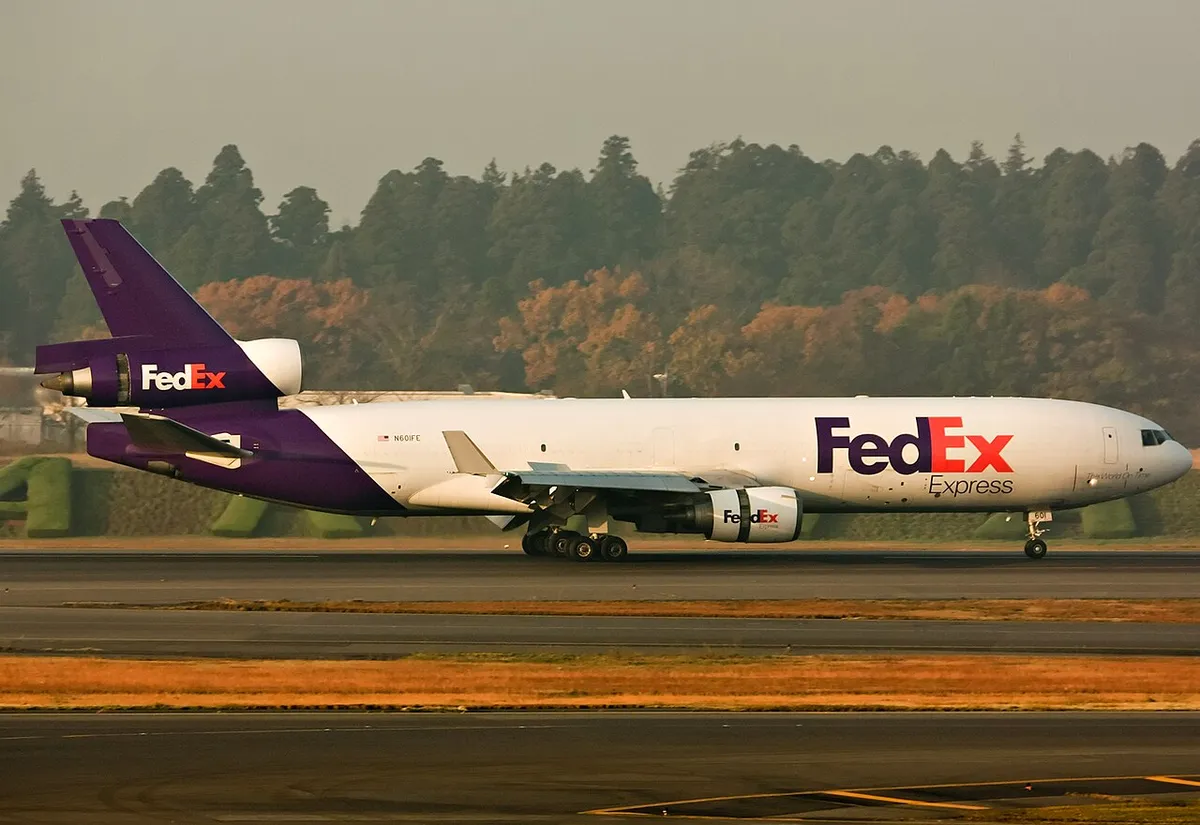 FedEx Express McDonnell Douglas MD-11F N601FE in side profile on the runway, showing the trijet layout with two underwing engines and the third engine buried in the tail fin.