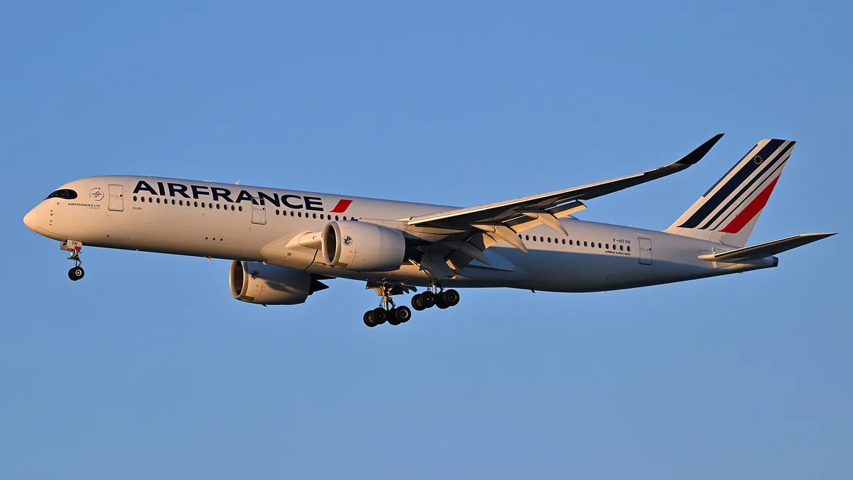 Air France Airbus A350-900 in golden-hour side profile on final approach, showing the raccoon-mask cockpit windows and curved upturned wingtip blades.