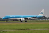 KLM Cityhopper Embraer E195-E2 PH-NXA in side profile on the runway, showing the swept pointed wingtips and the oversized Pratt & Whitney PW1900G engine pods.