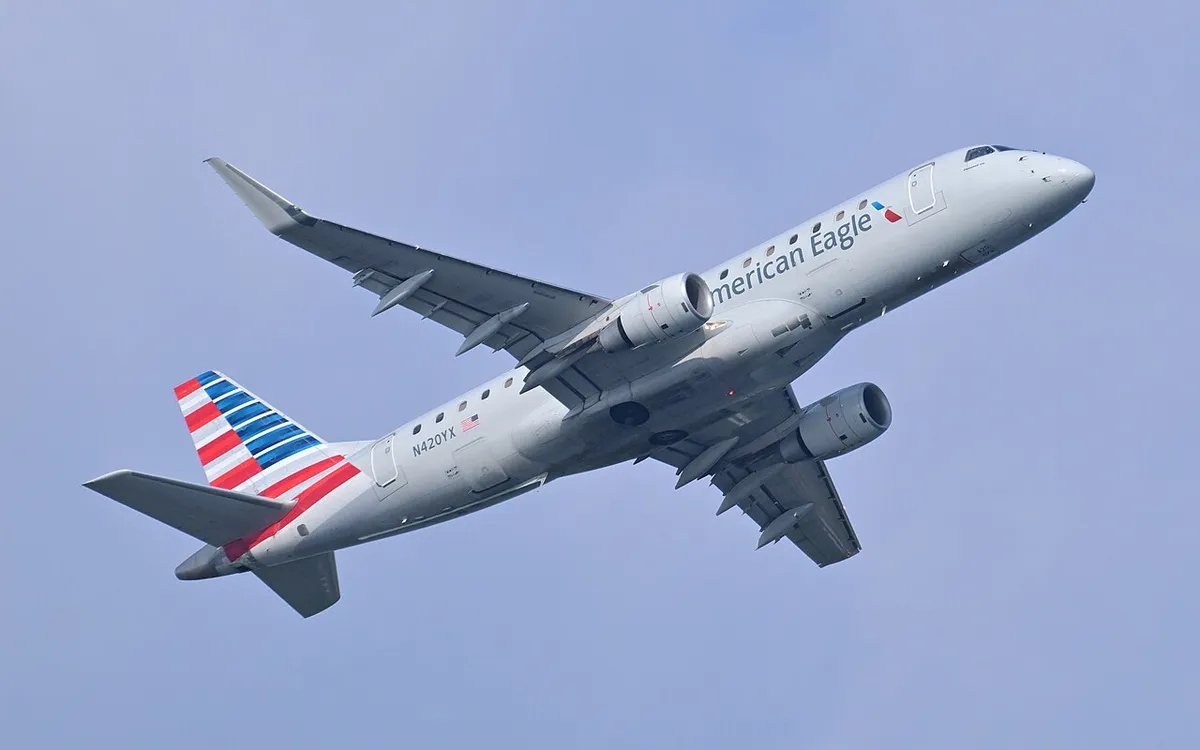 American Eagle Embraer E175 climbing away against the sky, three-quarter view showing its underwing engines, low tail, and squared-off cockpit windows.