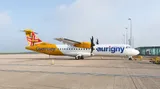 Aurigny Air Services ATR 72-600 parked on the apron in side profile against a clear sky, showing its high-mounted wing and twin turboprop engines.