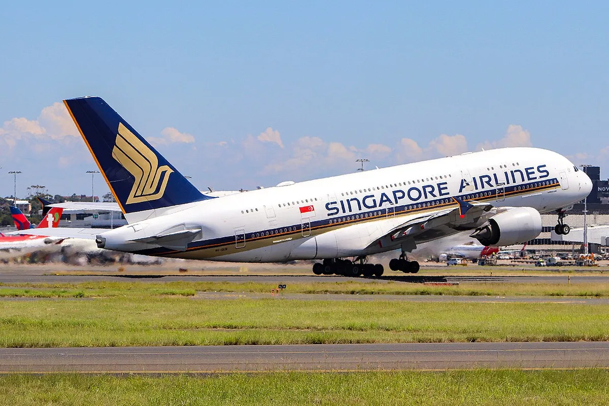 Singapore Airlines Airbus A380-841 climbing away from Sydney Airport in left side profile against a clear blue sky, showing its full double-deck body and four underwing engines.
