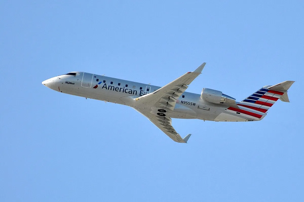 SkyWest Airlines CRJ200 climbing away in American Eagle livery, three-quarter view showing its plain wingtips and stubby, tightly coupled body.