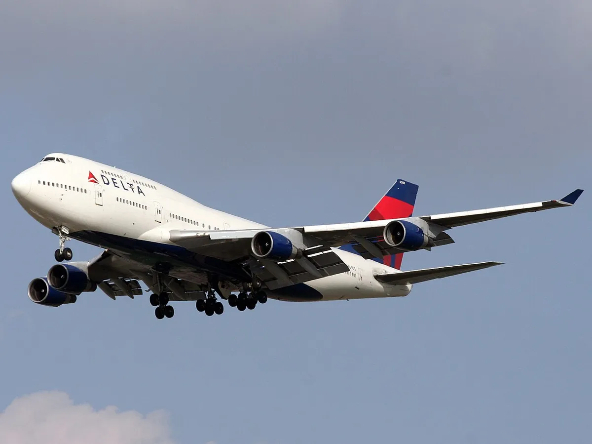 Delta Air Lines Boeing 747-451 seen from below on final approach into Ben Gurion Airport, landing gear extended, showing the underside profile and four underwing engines.