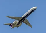 Delta Air Lines Boeing 717-200 climbing away from below, showing the T-tail and twin engines mounted high on the rear body.