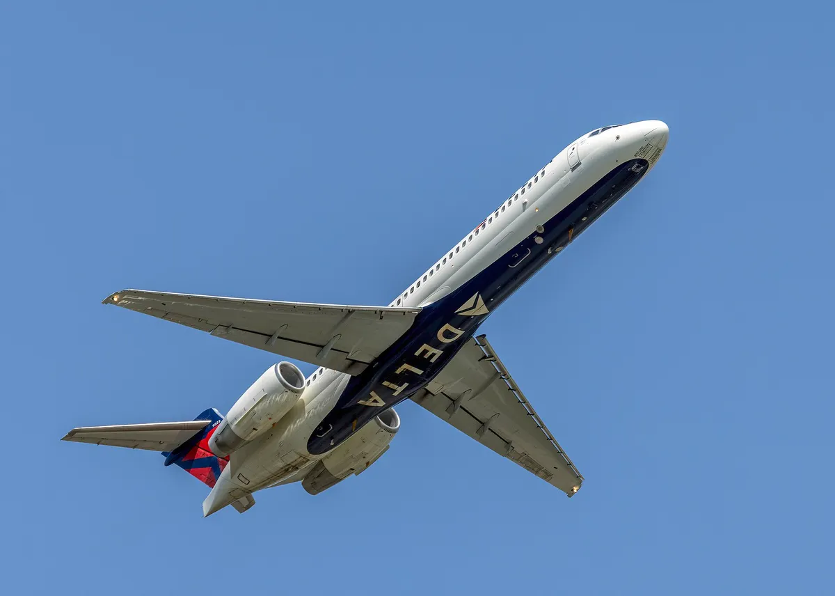 Delta Air Lines Boeing 717-200 climbing away from below, showing the T-tail and twin engines mounted high on the rear body.