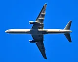 United Airlines Boeing 757-200 seen directly from below departing Boston, showing the underside outline and narrow, tapered wing.