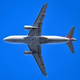 American Airlines Airbus A319-112 seen directly from below against a clear blue sky, showing the compact underside outline and flat wingtip fences.