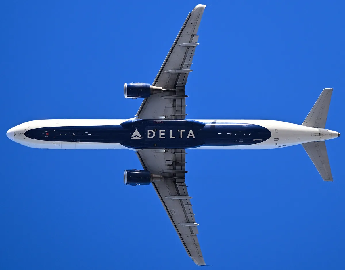 Delta Air Lines Airbus A321-211 seen directly from below against a clear blue sky, showing the stretched underside outline and slim, round ceo-generation engine pods.