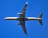 United Express Embraer E175 seen directly from below on departure, showing the underwing engines and enhanced wingtip blades.