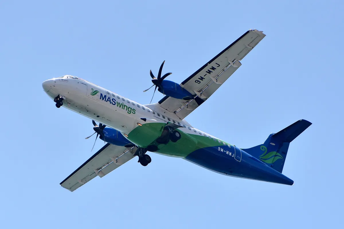 MASwings ATR 72 seen from below on final approach, showing the high wing, extended landing gear, and twin propellers.