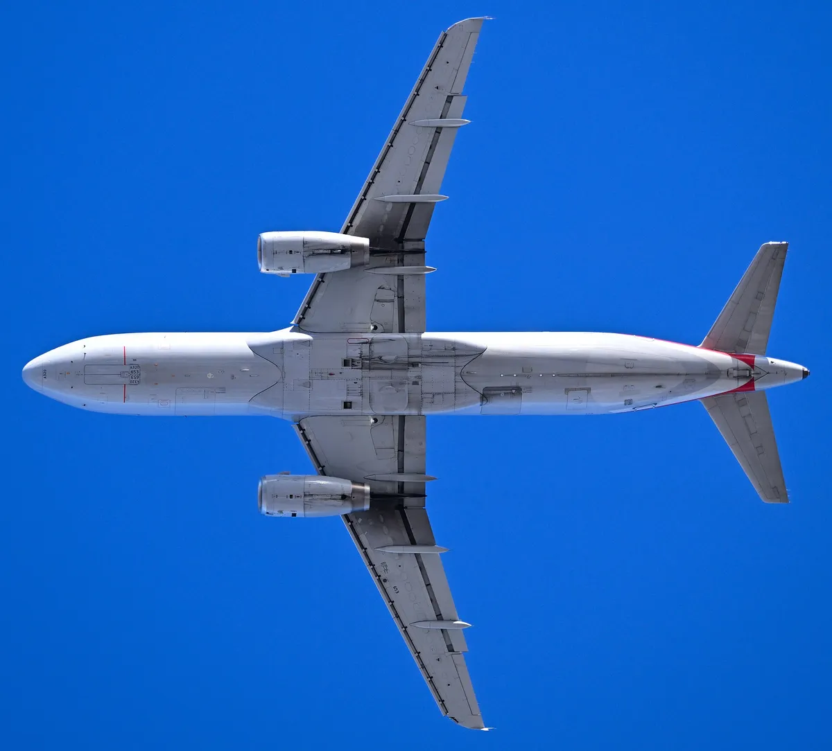 American Airlines Airbus A320-232 seen directly from below against a clear blue sky, showing the underside outline and slim, round ceo-generation engine pods.