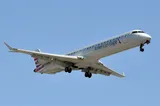 American Eagle CRJ900 seen from below on final approach, gear down, showing the upturned wingtip blades and rear-mounted engines.