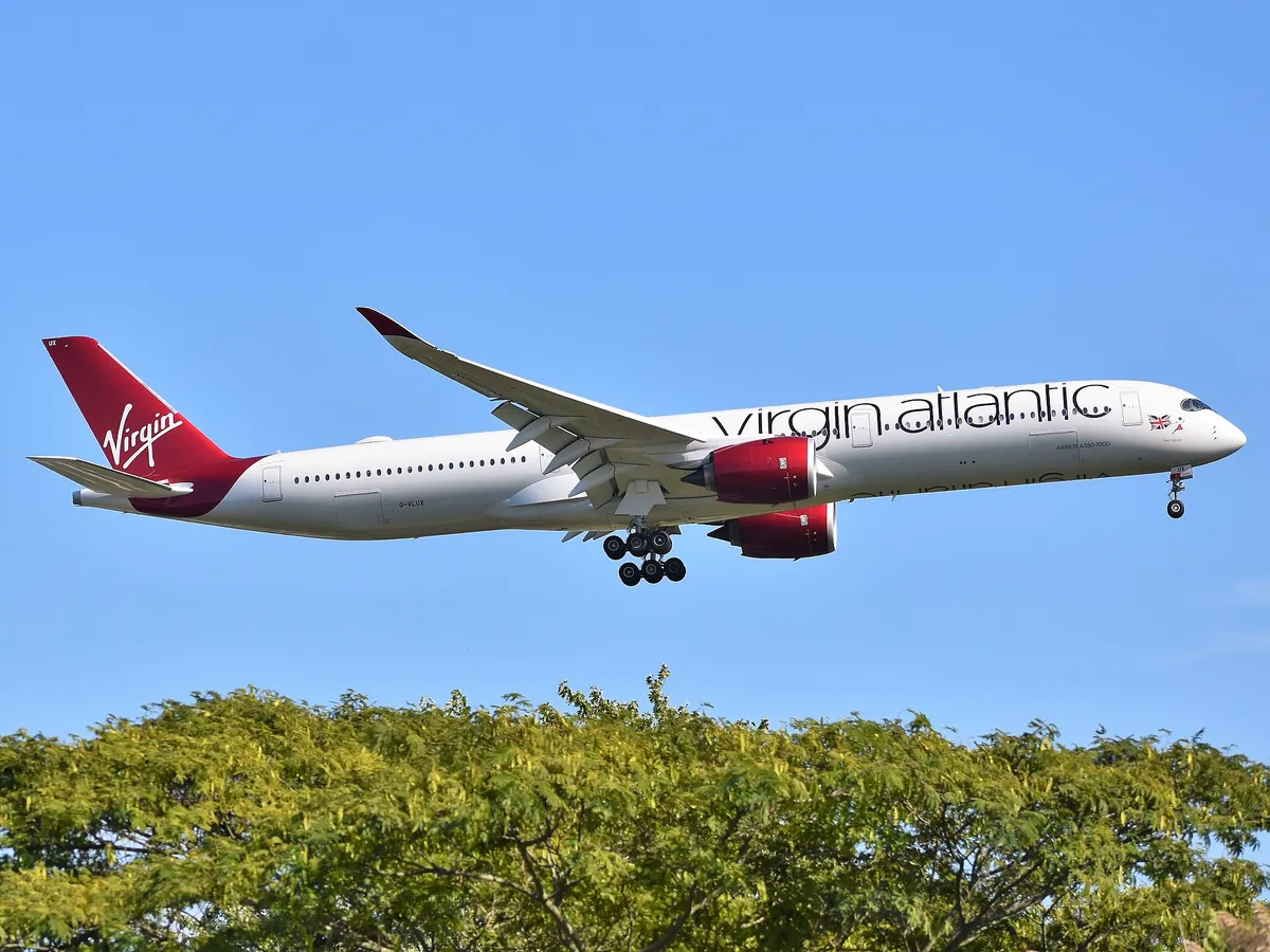Virgin Atlantic Airbus A350-1000 seen from below-quarter on approach with landing gear extended, showing the belly, bulkier engine pods, and the six-wheel main gear legs that distinguish it from the A350-900.