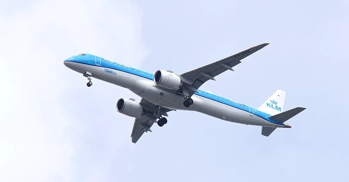 KLM Cityhopper Embraer E195-E2 PH-NXM climbing directly overhead with gear down, showing the underside outline, large engine pods, and swept wing.