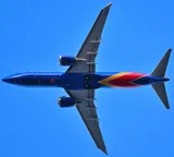 Southwest Airlines Boeing 737 MAX 8 seen directly from below departing Boston, showing the underside outline and the saw-tooth-edged engine pods.