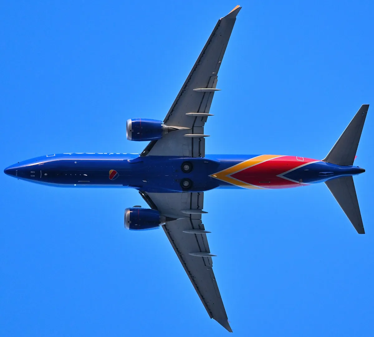 Southwest Airlines Boeing 737 MAX 8 seen directly from below departing Boston, showing the underside outline and the saw-tooth-edged engine pods.